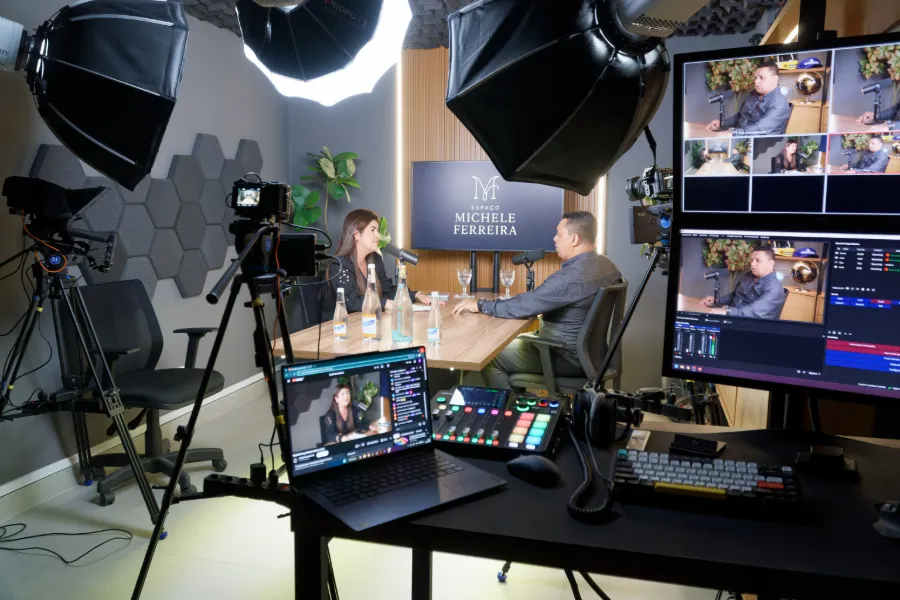 Gravação em andamento com duas pessoas na mesa, softboxes e câmeras posicionadas